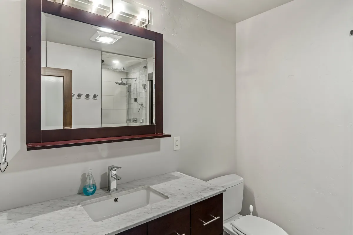 A bright and inviting half bathroom featuring a contemporary mirror, sink, and shower area. The space is well-lit and designed for comfort and convenience.