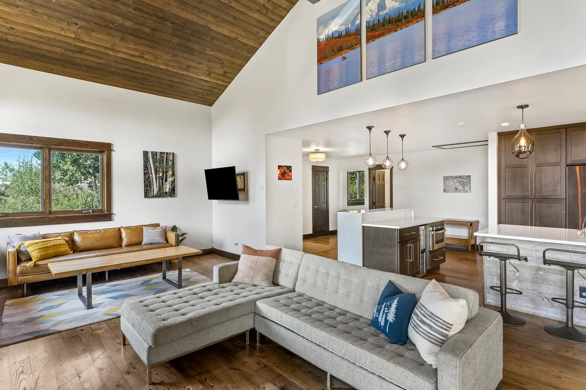 The living area features a comfortable sofa, a stylish coffee table, eye-catching artwork, and a view into the kitchen island. The setting feels cozy and inviting, ideal for relaxing after a day exploring Steamboat’s offerings.