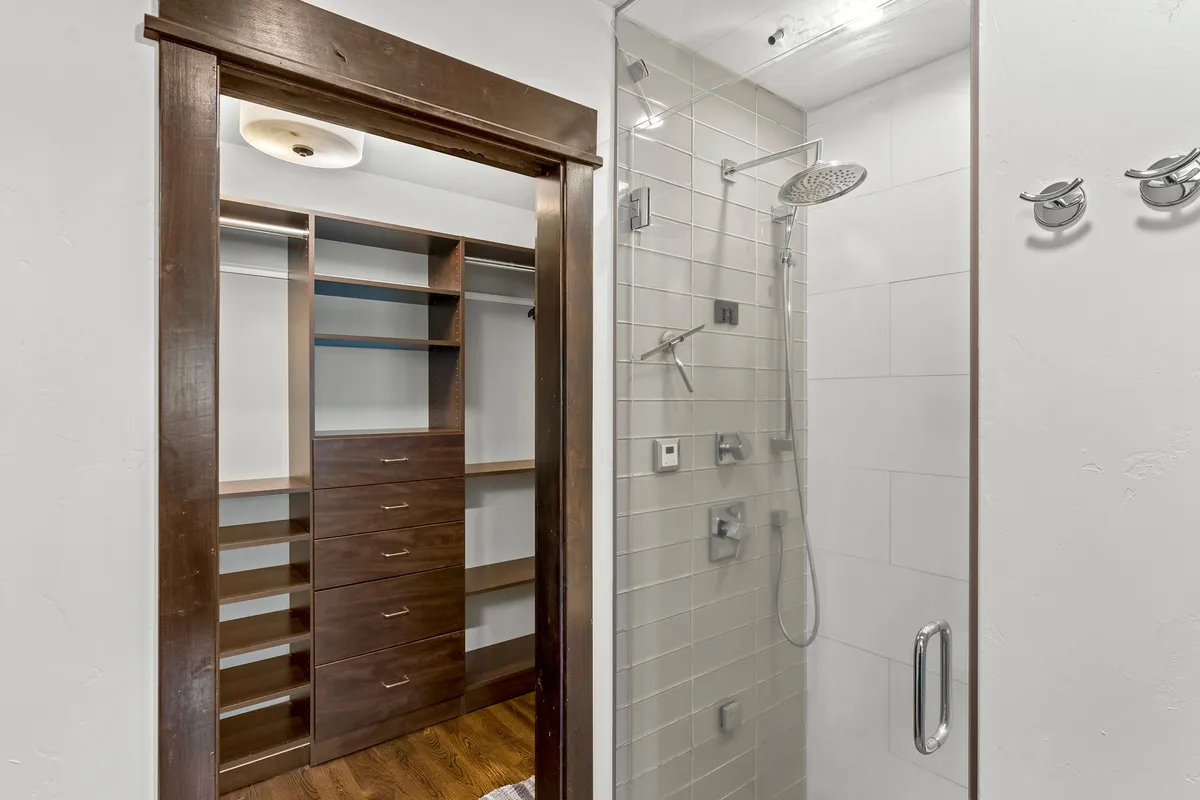 A modern bathroom with a spacious walk-in shower, stylish shower fixtures, and sleek wooden cabinetry. The area is brightly lit, organized, and gives off a spa-like ambiance, perfect for unwinding in comfort.