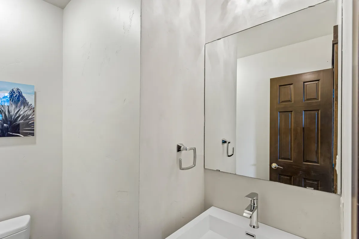 A tranquil bathroom scene with a large mirror, elegant sink, and minimalist artwork, bathed in soft light. The clean lines and uncluttered counter evoke a spa-like calm, perfect for unwinding at the end of the day.